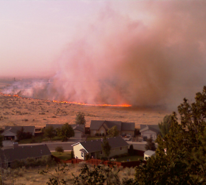 A picture of a fire occurring in the wildland urban interface (WUI). The fire looks to be approaching homes that are adjacent from the WUI